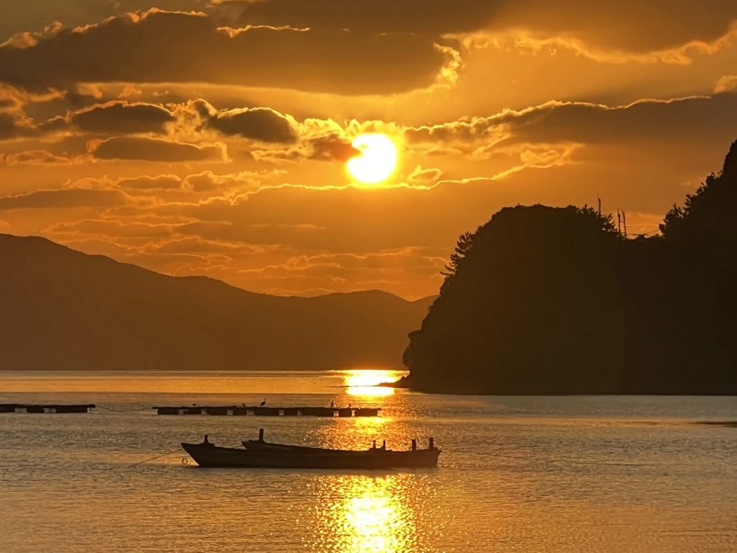 夕焼け空と水面に反射する夕日が美しい水辺の風景