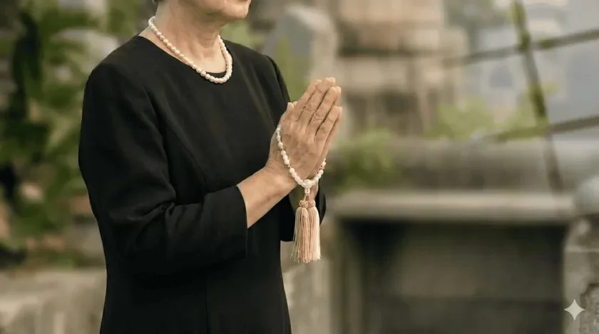 喪服を着用し、合掌する高齢の女性