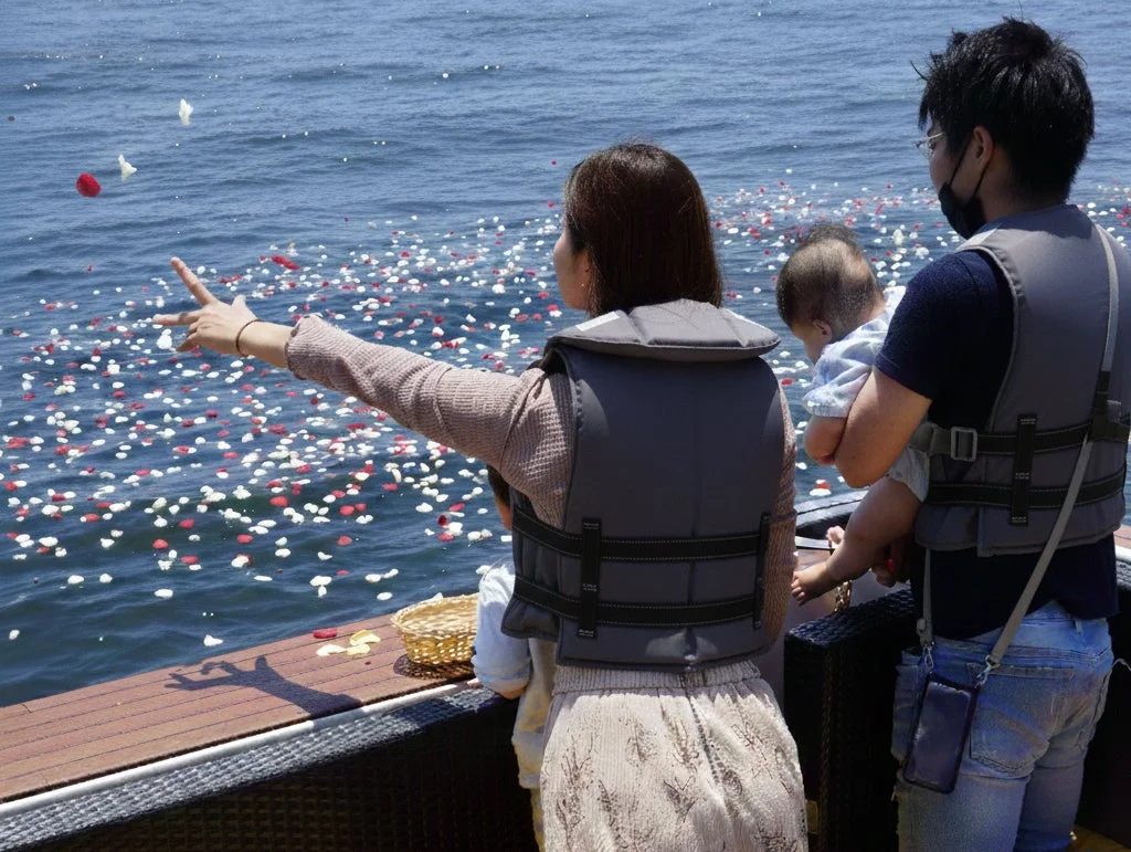 海上で花びらを撒く家族