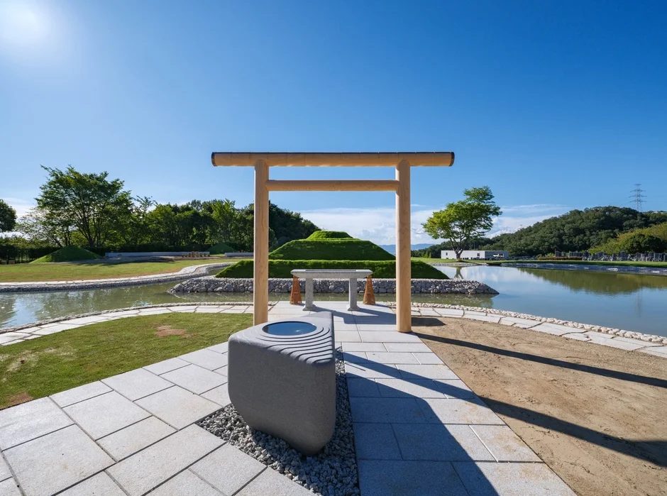 水辺に鳥居が立つ現代的な慰霊公園の風景