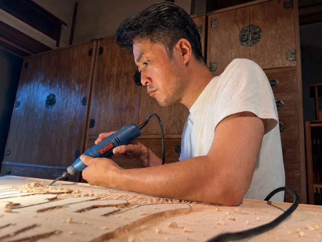 男性が電動工具で木材に彫刻