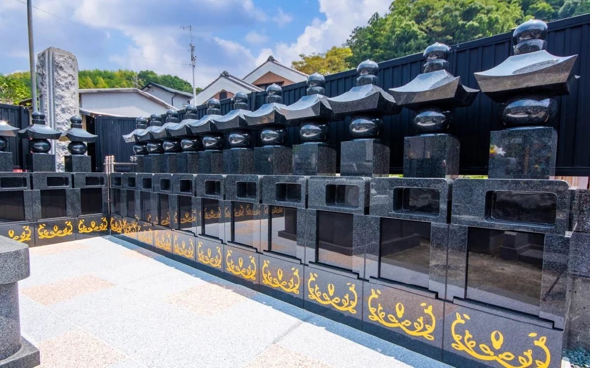 青空の下、現代的で整然と並ぶ黒い御影石の墓石群